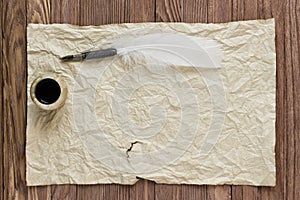 Quill with inkstand on vintage paper background and wood table