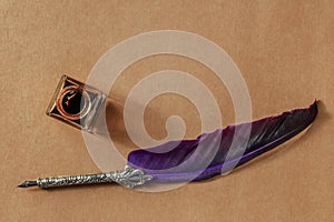 A quill pen with a vintage ink well, overhead flat lay shot on brown paper