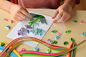 Quilling technique. Girl making decorations or greeting card. Paper strips, flower, scissors. Handmade crafts on holiday: Birthday photo