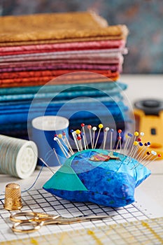 Quilting accessories on the background of a stack of bright quilting fabrics