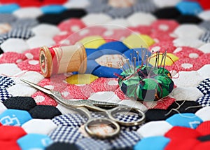 Quilting supplies on a colorful hexagon patterned quilt