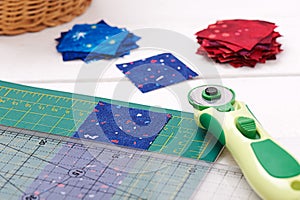 Quilting tools, piece of fabric prepared to cutting, two heaps cut off of fabrics