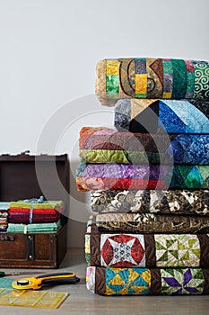 Quilts stacked, quilting accessories and wooden chest with stacks of fat quarters