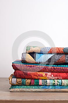 Quilts stacked on wooden table on white wall background