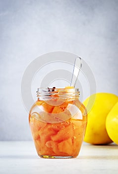 Quince jam or confiture in glass jar with cinnamon and anise on gray kitchen table background, copy space