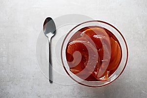 Quince jam in a glass bowl on a concrete background.