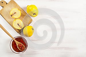 Quince jam in glass bowl with ripe fresh quinces on rustic table