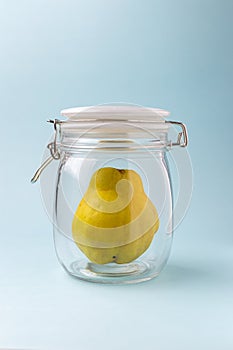 Quince ripe in the jar for conservation over blue background