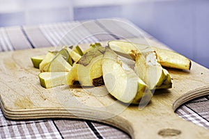 the quince, sliced to make jam, lies on a wooden chopping board