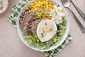 Quinoa breakfast bowl with lettuce, fried egg and corn