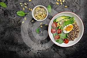 Quinoa buddha bowl with avocado, egg, tomatoes, spinach and sunflower seeds on a dark background. Homemade food. Healthy, clean