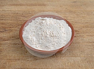 Quinoa flour in a bowl on a wood cutting board.