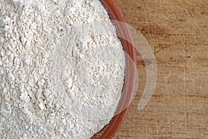 Quinoa flour in a bowl on a wood cutting board.