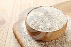 Quinoa flour in bowl on wooden table, closeup