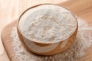 Quinoa flour in bowl on wooden table, closeup