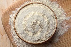 Quinoa flour in bowl on wooden table, top view