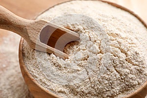 Quinoa flour in wooden bowl and scoop, closeup