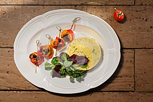 Quinoa with herbs and vegetable rolls of sweet pepper and eggplant in an oval white plate on an old wooden table. in the rays of