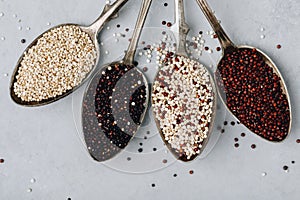 Quinoa. Red black white quinoa seeds in spoon on gray stone background, top view