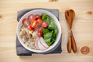 Quinoa salad with vegetables, raspberry and tomatoes on the wooden table. Super food for healthy and concept of balanced diet