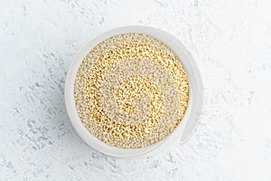 Quinoa seed in white bowl on white background. Dried cereals in cup, vegan food, fodmap diet. Top view, close up