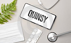 quinsy word on smartphone,stethoscope and green plant photo