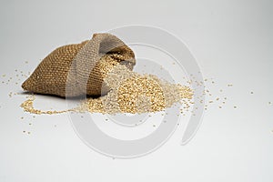 Quinua seeds in a small burlap bag with white background