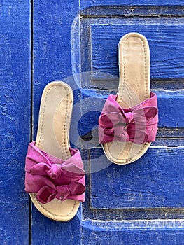 Quirky, elegant pink women's sandals on blue door, Essaouira, Morocco