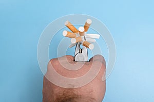 Quit smoking concept. Crumpled cigarettes clamped in pliers on a blue background. Willpower to give up a bad habit