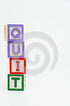 QUIT word wooden block arrange in vertical style on white background and selective focus