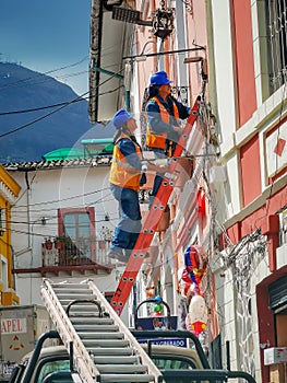 Quito, ECUADOR - 02 October 2019: Electricians are climbing on electric poles to install and repair power lines
