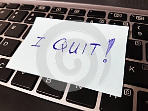 Quitting a job concept using a sticky pad with the word `I QUIT!` written on it and left on top of a keyboard