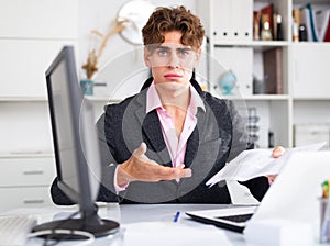 Quizzical man working on his laptop in white room