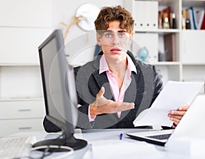 quizzical man working on his laptop in white room