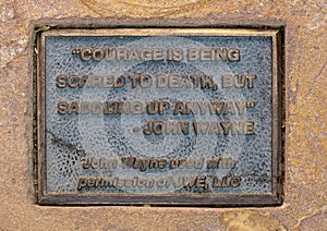 Quote beneath a sculpture of a saddle on a fence rail in Welcome Plaza of Oklahoma State University in Stillwater, Oklahoma.