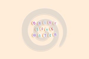 Quote Drink some water made of round beads with multicolored letters.