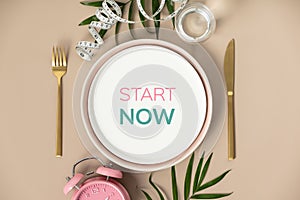 Quote Start now Composition with cutlery, plate, measuring tape and alarm clock on color background