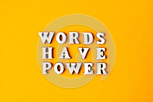 Quote WORDS HAVE POWER made out of wooden letters on bright yellow background