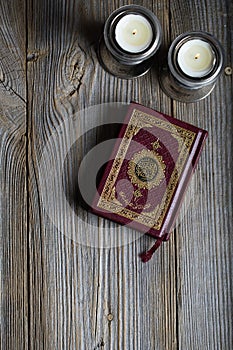 Quran and candles on a wooden surface.