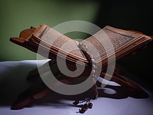 Quran-holy book of Muslims, an open book on rehal or wooden book rest with tasbih or islamic prayer beads