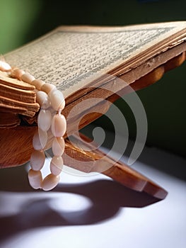 Quran-holy book of Muslims, an open book on rehal or wooden book rest with tasbih or islamic prayer beads
