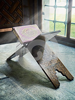 A Quran over a wooden stand enveloped in a ray of divine light.