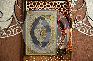 Quran, tasbeeh and glasses on a prayer mat