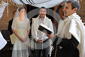 Rabbi blessing Jewish bride and a bridegroom in Jewish wedding ceremony