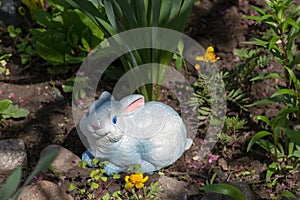 Rabbit garden figurine under a bush