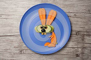 Rabbit made of carrot on plate and table