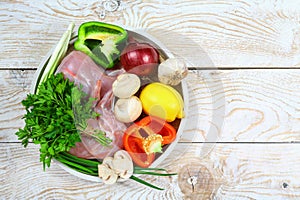 Rabbit raw meat, vegetables, mushrooms spices on a round tray, rustic background. Flat lay top view, place for text