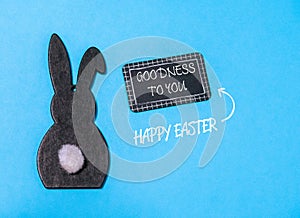 Rabbit is sitting on a blue background with a sign that says Goodness to you photo