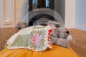 a rabbit toy pet resting in front of the fireplace in winter photo