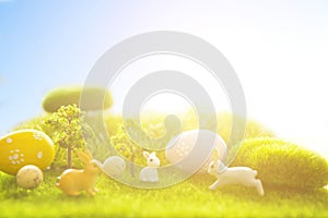 Rabbits with easter eggs on green meadow over sundown. Cute Little easter bunny on spring flowers and green grass